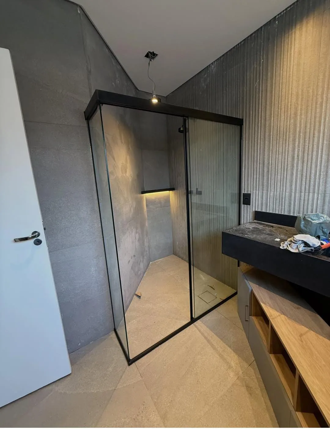 Box de canto em vidro com perfis pretos em banheiro de porcelanato cinza — vidraçaria em Lavras